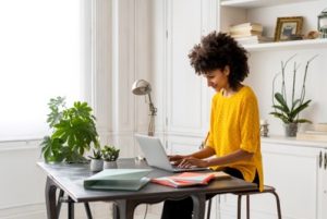 Femme avec un vêtement jaune faisant du télétravail.