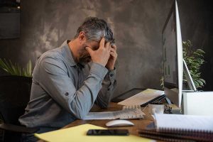 Un homme fatigué et angoissé par son travail, devant son écran