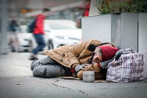 Une personne itinérante allongée au sol en ville par temps froid.